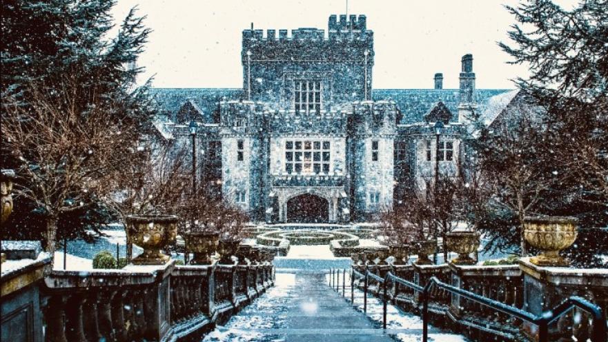 Hatley Castle covered in snow. The surrounding trees do not have leaves on them.