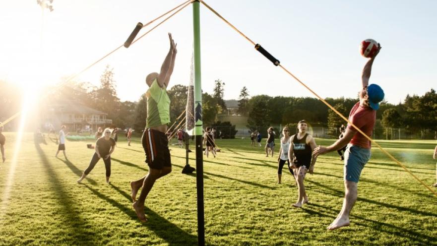 People playing volleyball outside in the lawn.