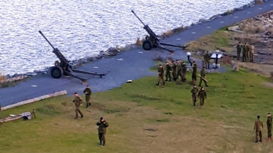 Soldiers and artillery guns pointing towards the water.