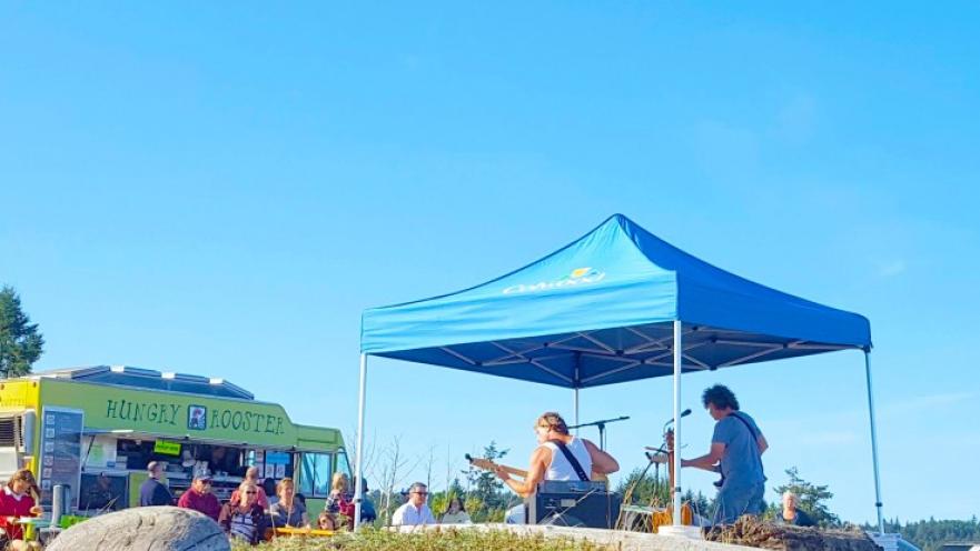 Performers playing guitar on stage covered by blue tent.