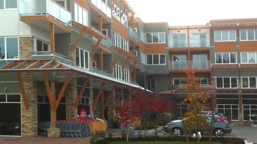 Exterior of building. There is a car parked near the entrance to one of the buildings.
