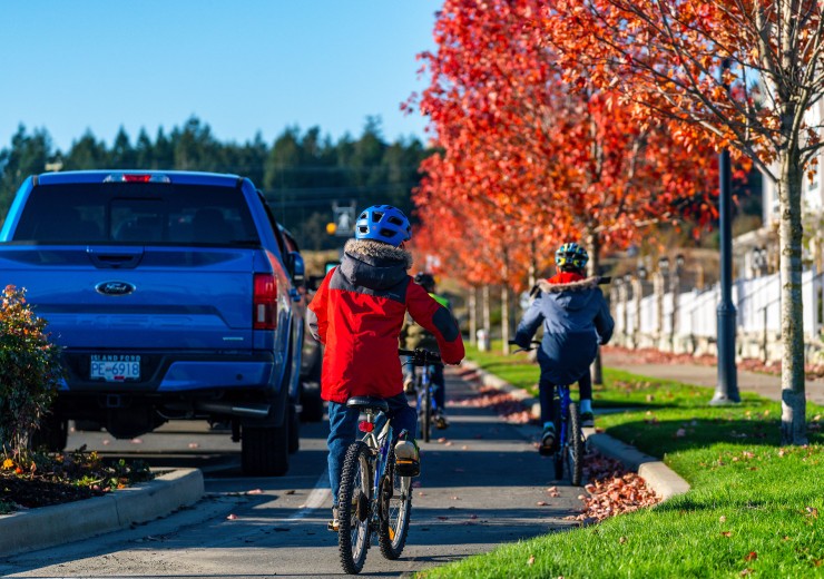 Kids riding bicycles in a bike lane with fall trees