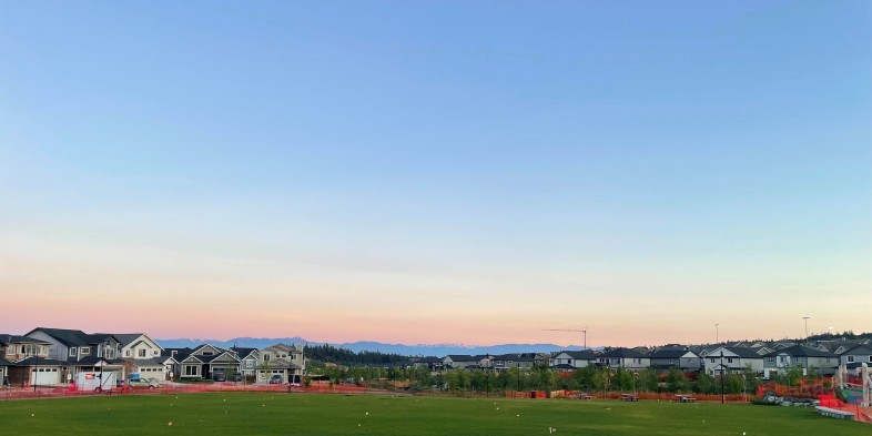 meadow park green at twilight surrounded by homes with the mountains in the distance