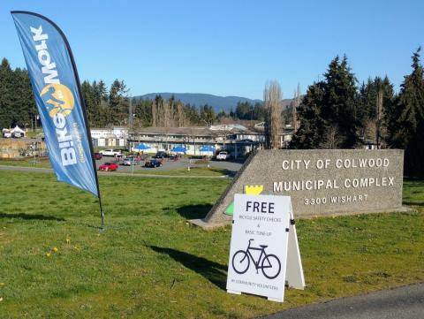 Bike safety check event at the City of Colwood Municipal Complex with a sign offering free bicycle safety checks and basic tune-ups.