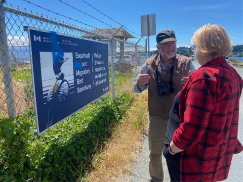 people talking by a waterfront sign
