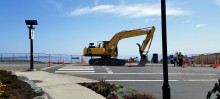 excavator at the intersection with the ocean in the background